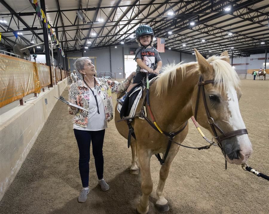  Iris looks up to a boy on a horse and smiles. 